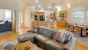 A spacious living area with a leather sofa, a dining table, and a kitchen in the background. - Game Room & On-site Golf Course! Lake Almanor Home (Westwood)