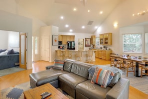 A spacious living area with a leather sofa, a dining table, and a kitchen in the background. - Game Room & On-site Golf Course! Lake Almanor Home (Westwood)