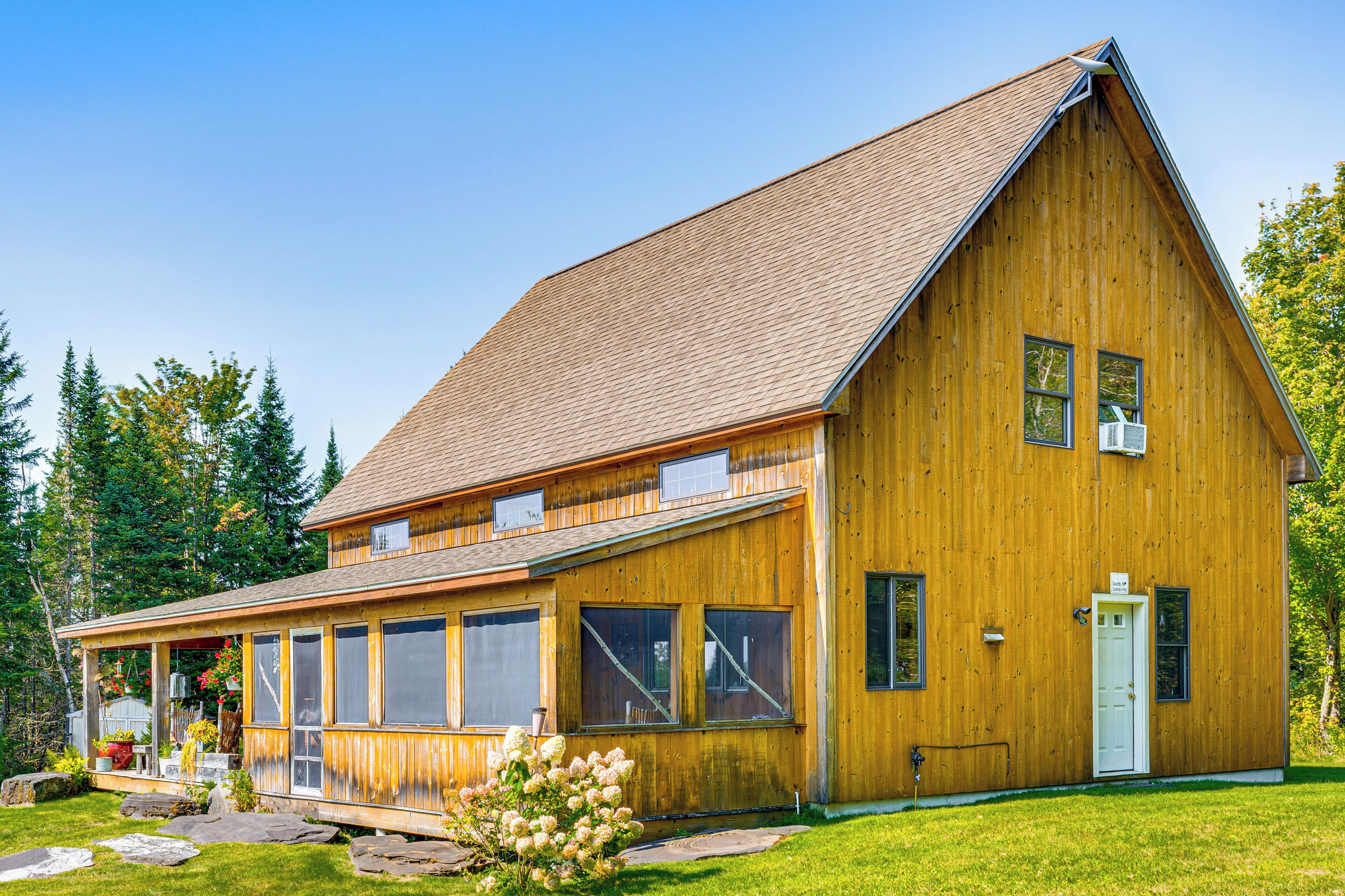A wooden building with a sloped roof, large windows, and a door.