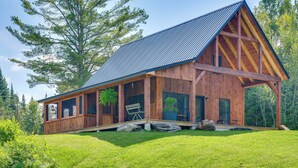 Une cabane en bois avec un toit en pente, de grandes fenêtres et une véranda couverte.