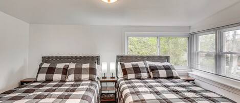 A bedroom with two beds, a window, and a ceiling light.