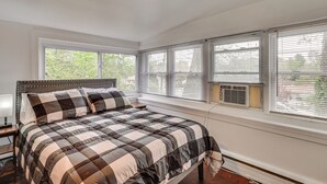 A bedroom with a large bed, multiple windows, and an air conditioning unit. - Nature & City Access! Family Home in North Jersey (Lincoln Park)
