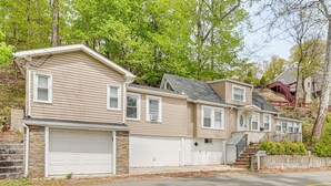 A two-story residential building with a garage, a brick foundation, and a staircase leading to a second level. - Nature & City Access! Family Home in North Jersey (Lincoln Park)