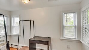 A room with white walls, a ceiling light fixture, a window with blinds, and a small table. - Nature & City Access! Family Home in North Jersey (Lincoln Park)