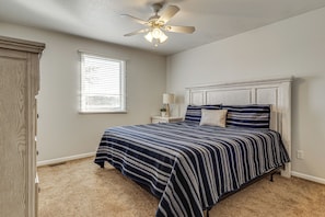 A bedroom with a bed, a ceiling fan, a window with blinds, a nightstand with a lamp, and a wardrobe. - Private Dock & Large Deck! Jimmerson Lake Escape (Angola)