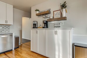 Cocina con armarios blancos, una cafetera y un cartel que dice 'Lake House'.