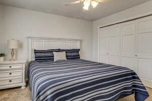 Un dormitorio con cama, mesita de noche, lámpara y armario.