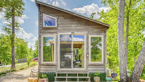 A wooden cabin with a large window, a bench, and potted plants. - Tiny Cabin Getaway in the Tennessee River Valley (Rogersville)