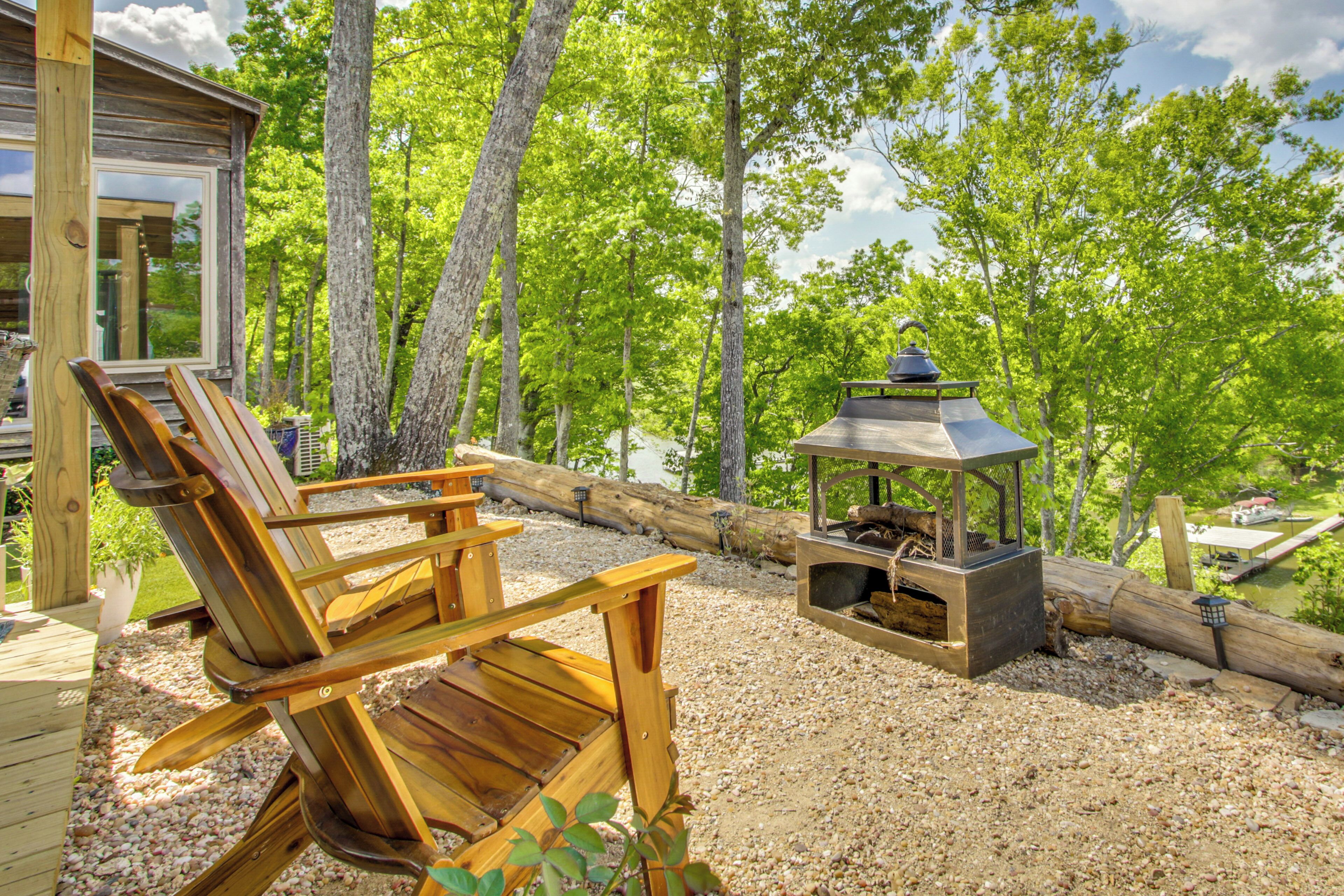 Une terrasse en bois avec une chaise, un foyer et un chalet situés dans une zone boisée.