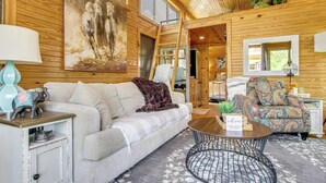 A cozy interior with a sofa, patterned armchair, and a round coffee table. - Tiny Cabin Getaway in the Tennessee River Valley (Rogersville)