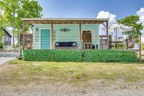 A small, rustic building with a green exterior, a wooden porch, and a metal fence. - Couple's Retreat w/ Creek Access in Rogersville (Rogersville)