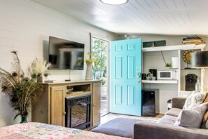 A room with a bed, a television, a microwave, a coffee maker, and a door leading outside. - Couple's Retreat w/ Creek Access in Rogersville (Rogersville)