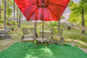 An outdoor seating area with wicker chairs, a table, and a red umbrella. - Creekside Couple's Glamping Retreat in Rogersville (Rogersville)