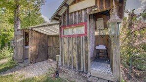 Eine rustikale Holzhütte mit einer Willkommensschild, einer kleinen Veranda und einem sichtbaren Badezimmer.