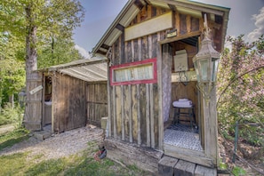 A rustic wooden cabin with a welcome sign, a small porch, and a visible bathroom.