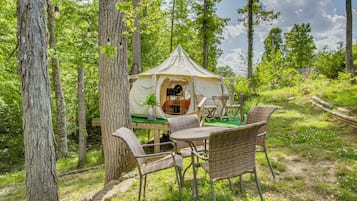 A tent with a table and chairs in a forest.