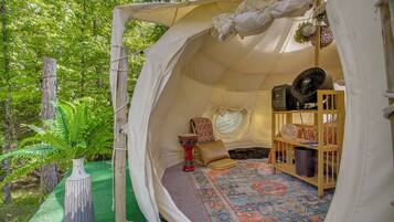 A tent with a patterned rug, a red decorative item, and a fan.