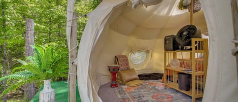 A tent with a patterned rug, a red decorative item, and a fan.