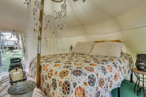 A tent with a bed, a basket with candles, and a hanging dreamcatcher.