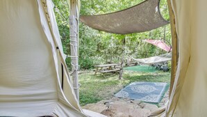 A tent with a view of a picnic area, a hammock, and a patterned mat. - Unique Glamping Tent in Tennessee River Valley (Rogersville)