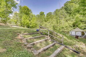 A campsite with a wooden staircase leading to a tent, surrounded by trees and grass.