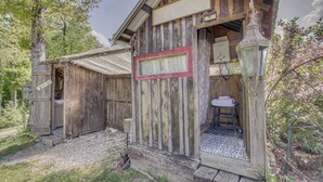 A rustic wooden cabin with a welcome sign, a small porch, and a visible bathroom. - Unique Glamping Tent in Tennessee River Valley (Rogersville)