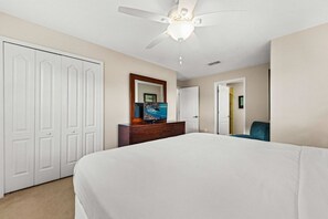A hotel room with a bed, a dresser, a ceiling fan, and a door leading to another room. - Private Pool·Lake View·BBQ·Mins to Disney (Kissimmee)