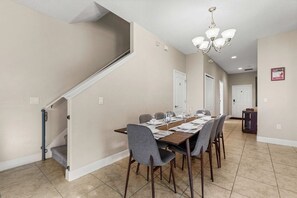 Uma sala de jantar com uma mesa comprida, cadeiras e um candelabro.
