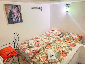 A bedroom with a bed, a chair, a wall-mounted light, and a framed picture. - Dar Lala Ghita (Fes)