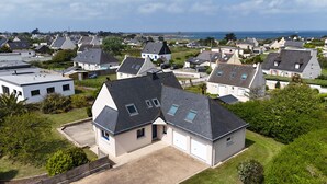 A residential area with houses featuring pitched roofs, a driveway, and a view of the sea. - COMFORTABLE VILLA 5 MINUTES WALK FROM GRÈVE BLANCHE BEACH (Plouguerneau)