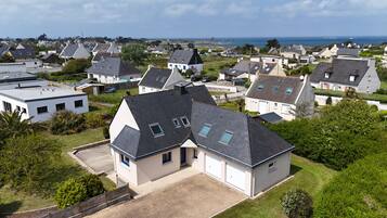 Een woonwijk met huizen met zadeldaken, een oprit en uitzicht op zee.