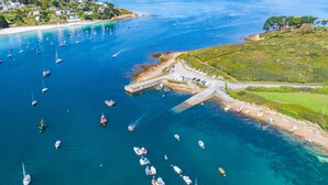 An aerial view of a coastal area with numerous boats docked at a pier, surrounded by lush greenery and a residential area in the background. - COMFORTABLE VILLA 5 MINUTES WALK FROM GRÈVE BLANCHE BEACH (Plouguerneau)