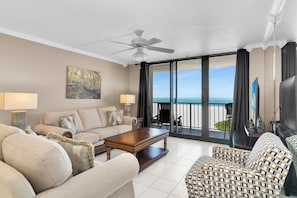 Ein Wohnzimmer mit Sofa, Couchtisch, Fernseher und einem Balkon mit Meerblick.
