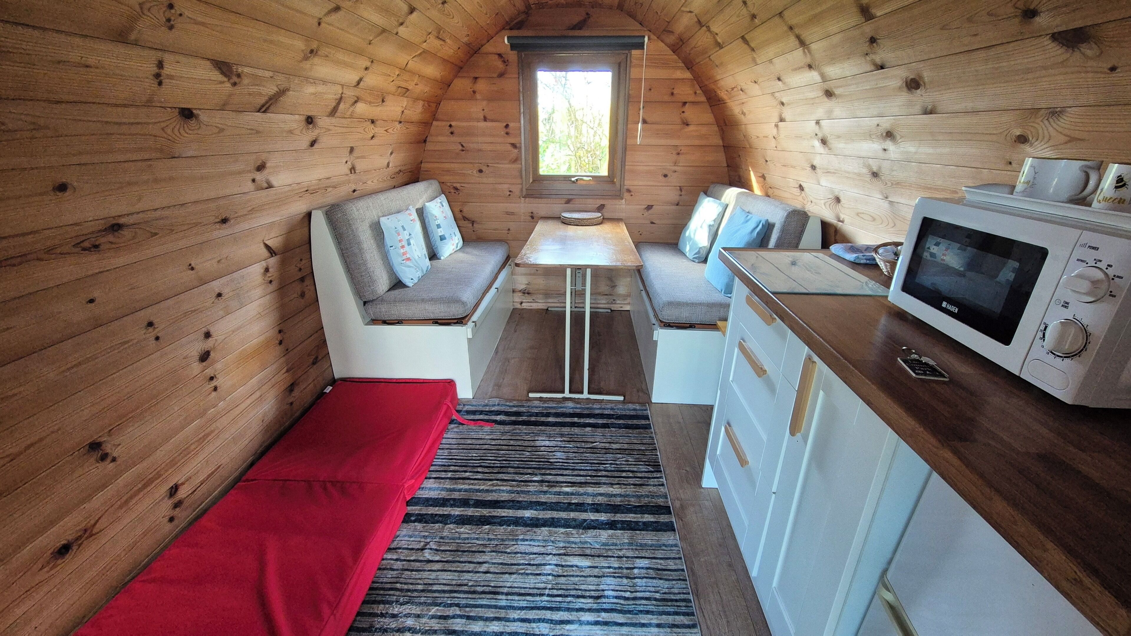 L’intérieur chaleureux d’un chalet, avec un revêtement en bois, une table à manger, un coin salon et un four à micro-ondes.