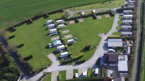 An aerial view of a campsite with RVs, a road, and residential buildings.