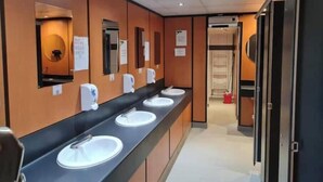 A long corridor with multiple sinks and mirrors, each with a soap dispenser.