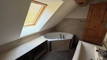 Ein modernes Badezimmer mit Oberlicht, Badewanne, Waschbecken und Holzschränken.