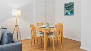 A dining area with a wooden table, four chairs, a floor lamp, and a painting on the wall. - Windsor Castle Views - Spacious Flat - By Tempstay (Windsor)