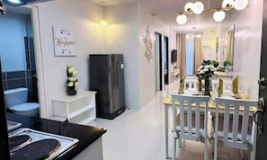 Una cocina moderna con refrigerador, una mesa de comedor con sillas y una lámpara de pared.