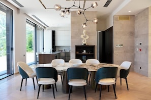 A modern dining area with a marble table, teal chairs, and a unique pendant light. - Villa Mandragora Seafront Villa with Private Pool and Dock (Orahovac)
