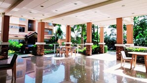 Un espacio al aire libre techado con piso reflectante, asientos y vistas a un edificio con señalización.