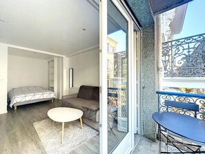 A modern apartment with a balcony, a sofa, a small round table, and a bed. - Sweet Home Marceau (Cannes)