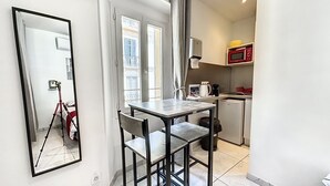 Cozinha compacta com área de refeições, um espelho e vista para a varanda.