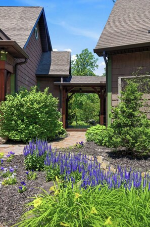 Ein Gebäude mit Holzfassade, einer überdachten Veranda und einem Garten mit verschiedenen Pflanzen und Blumen.