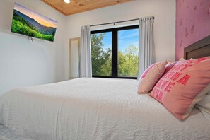 Una camera da letto con un letto grande, una finestra con tende, un quadro al muro e una parete rosa con stelle.