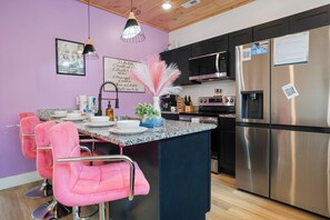 Una cucina moderna con sgabelli da bar rosa, elettrodomestici in acciaio inossidabile e un cartello con la scritta 'To Do List'.