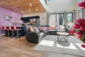 Ein modernes Wohnzimmer mit einem Ecksofa, einem Couchtisch und einer Küche im Hintergrund.