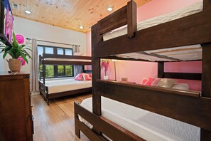 Una habitación con dos literas, un escritorio de madera, una planta en maceta y una ventana con vistas.