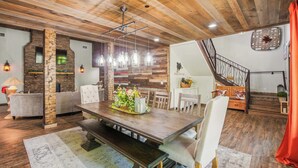 A dining area with a wooden table, benches, and hanging light fixtures. - Luxe Riverfront Cabin ・ Walk to Parkway・Hot Tub (Pigeon Forge)