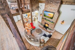 Amplia sala de estar con un sofá curvo, una chimenea y un televisor montado en una pared de ladrillo.